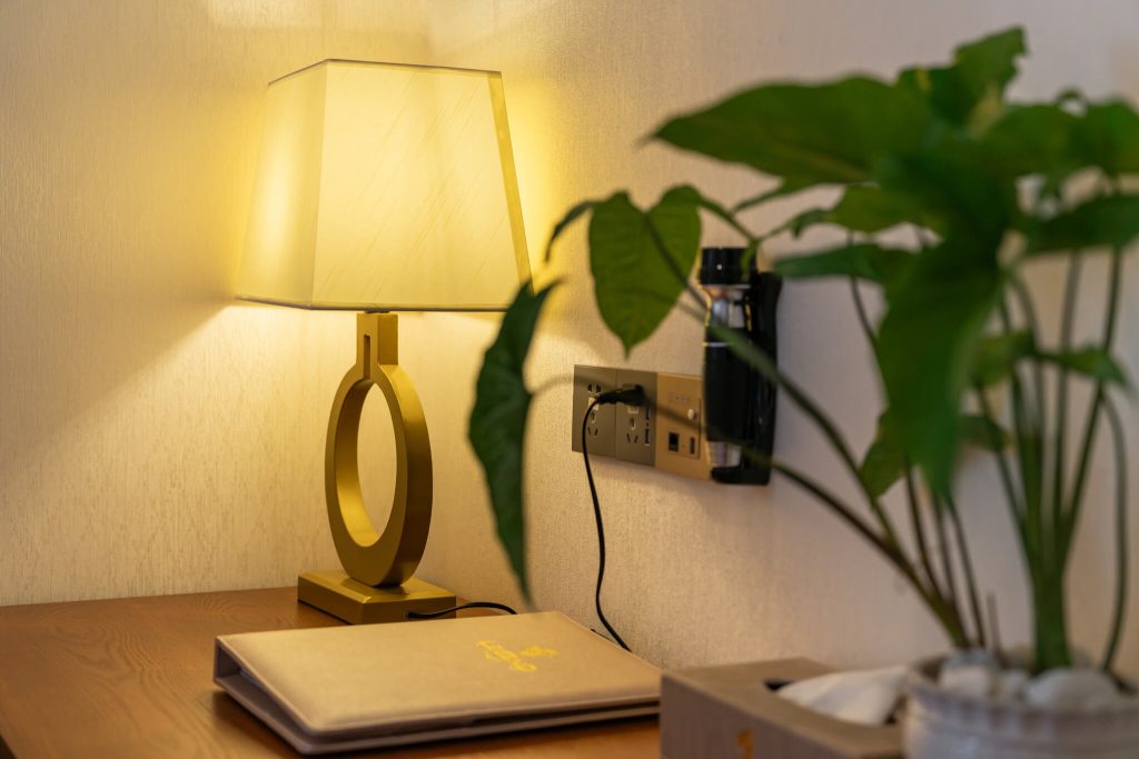 Royal Legend Room: in-room catalogue menu on side table next to modern lamp at Legend Hotel & Resort Sihanoukville, Cambodia.